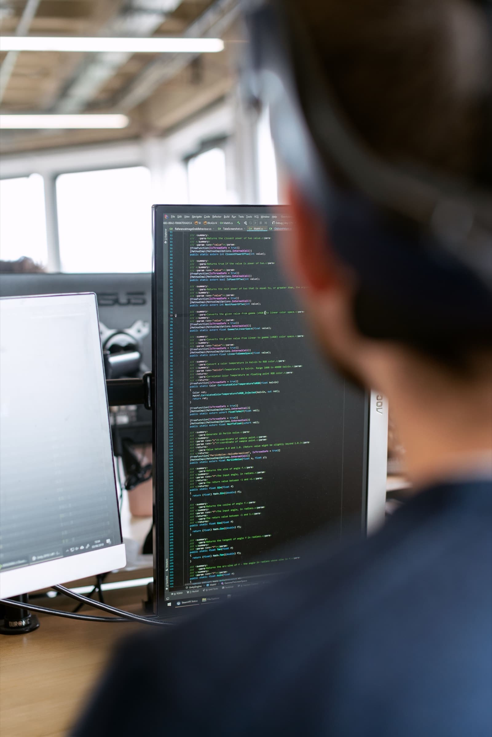 Ontwikkelaar werkt aan een staand scherm vol code